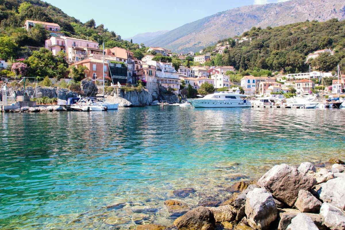 Gruppo di escursionisti con zaini e bastoncini che attraversano un sentiero panoramico con vista sui canyon del Parco della Murgia Materana, primavera, cielo azzurro