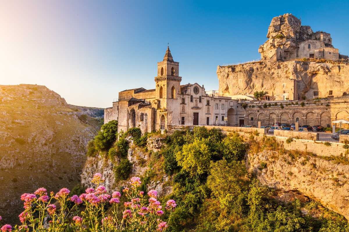 Scorcio panoramico sui Sassi di Matera al tramonto, tetti in tufo e luci calde, atmosfera accogliente
